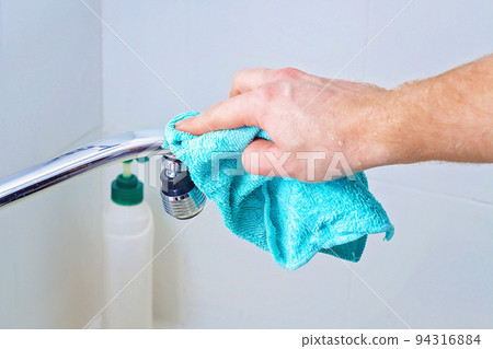 A man wipes a mixer tap, faucet with a rag A man wipes a mixer tap, faucet with a rag 94316884