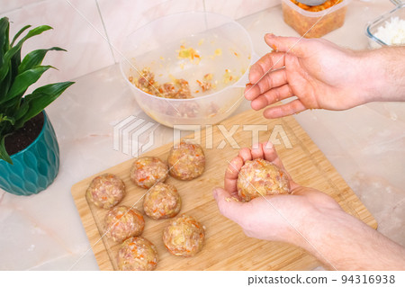 A man sculpts lazy cabbage rolls from minced meat 94316938