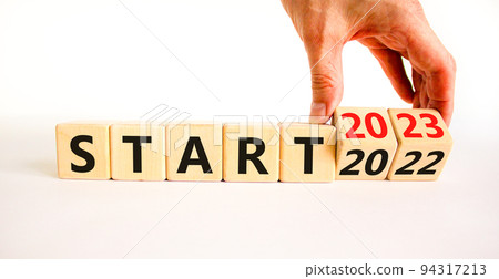2023 start new year symbol. Businessman turns a wooden cube and changes words Start 2022 to Start 2023. Beautiful white table white background, copy space. Business 2023 start new year concept. 94317213