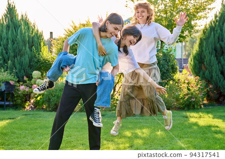Three teenage friends having fun outdoor, sunny summer day on the lawn 94317541