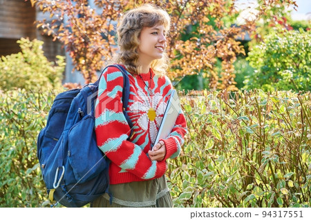 Teenage female student with laptop backpack in hands, outdoor 94317551