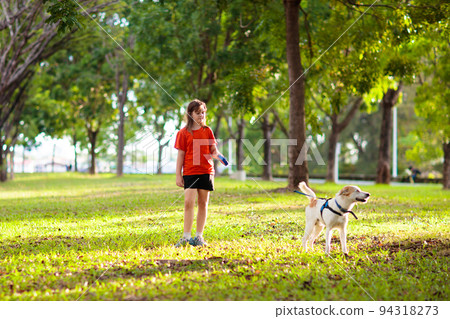 Child walking dog. Kids and puppy. Girl and pet 94318273