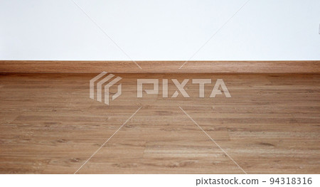 Laminate wood floor with blank white wall 94318316