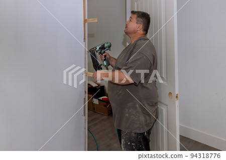 The interior doors of a new house are being installed by a carpenter trim worker 94318776