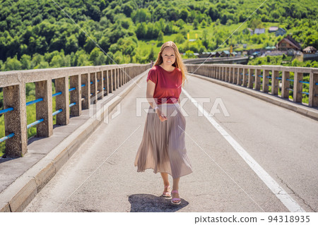 Montenegro. Woman tourist in background of Dzhurdzhevich Bridge Over The River Tara. Travel around Montenegro concept. Sights of Montenegro Portrait of a disgruntled girl sitting at a cafe table 94318935