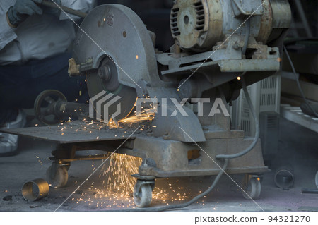 Male worker cutting metal with a large cutting machine 94321270