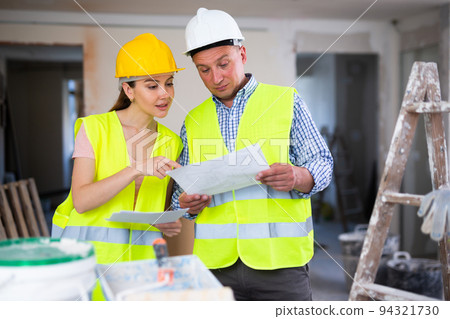 Man and woman builders talking in house Man and woman builders talking in house 94321730
