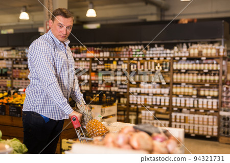 Confident buyer with shopping cart in grocery hypermarket 94321731