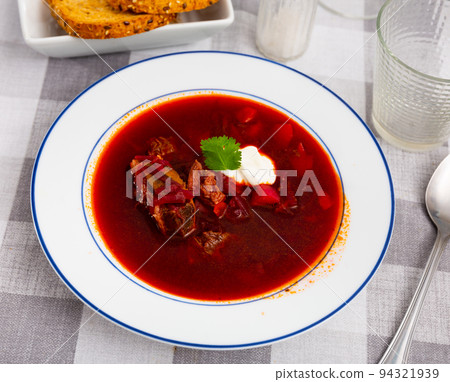 Traditional Ukrainian or Russian beetroot soup with beef decorated by sour cream and parsley Traditional Ukrainian or Russian beetroot soup with beef decorated by sour cream and parsley 94321939
