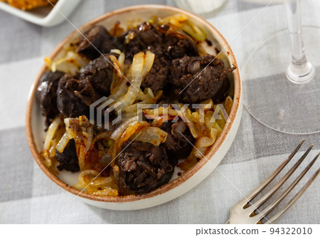 Delicious fried morcilla and grilled onion served on plate 94322010