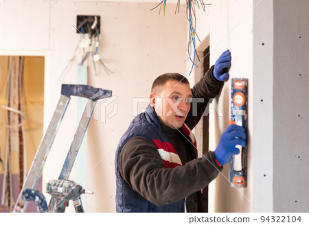 Builder checks the vertical of the wall using level 94322104
