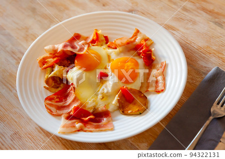 Bacon with fried potato and egg served on plate on table 94322131