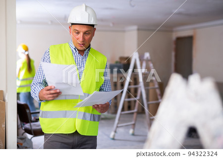 Man builder examining project documentation in apartment 94322324
