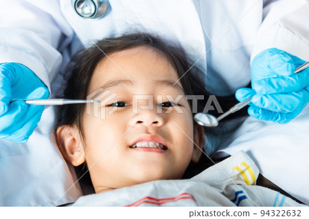 Doctor examines oral cavity of little child uses mouth mirror to checking teeth cavity 94322632