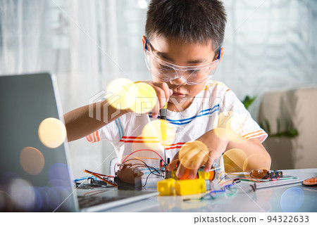Asian kid boy assembling the Arduino robot car homework project at home Asian kid boy assembling the Arduino robot car homework project at home 94322633