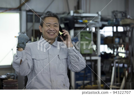中間人在工廠打電話時笑著擺出膽量的姿勢 94322707