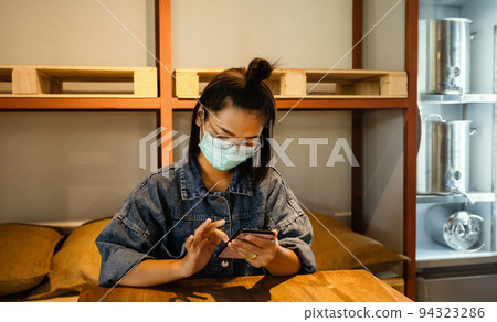 Asian businesswoman slides her phone to check products in front of the beer keg freezer. Small business concept Asian businesswoman slides her phone to check products in front of the beer keg freezer. Small business concept 94323286