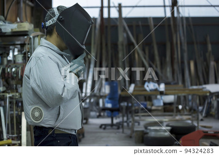工廠男工穿著空調工作服,戴著電焊面罩 工廠男工穿著空調工作服,戴著電焊面罩 94324283