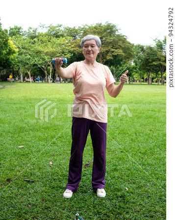 Portrait of mature asian woman 60s wearing sports clothing doing arm work out and lifting dumbbell exercise with relaxation for healthy in park outdoor. Portrait of mature asian woman 60s wearing sports clothing doing arm work out and lifting dumbbell exercise with relaxation for healthy in park outdoor. 94324792