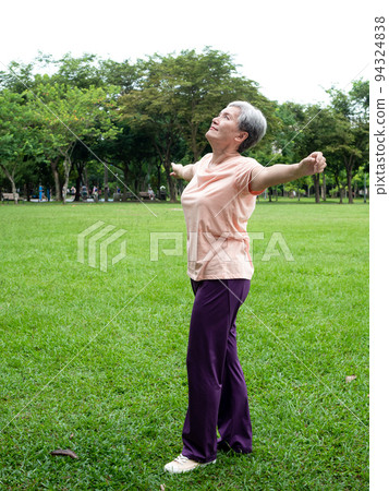 Portrait of senior adult elderly asian woman 60s smiling standing and stretch her arms relax and enjoy with nature fresh air in the park. Portrait of senior adult elderly asian woman 60s smiling standing and stretch her arms relax and enjoy with nature fresh air in the park. 94324838