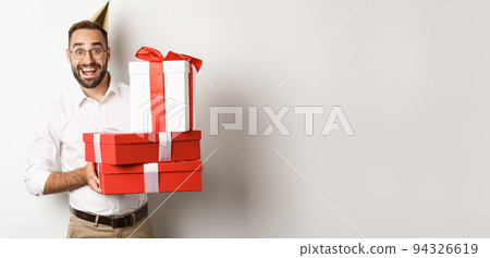 Holidays and celebration. Happy man receiving gifts on birthday, holding presents and looking excited, standing over white background 94326619