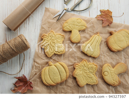 Cookies shaped like pumpkin and leaves on rustic wood background 94327397