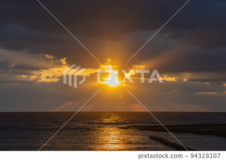 夕陽透過雲層照耀在地平線上 94328107