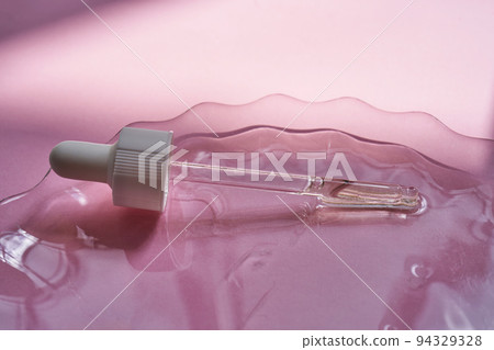 Dropper with serum or cosmetic oil on a pink background. 94329328