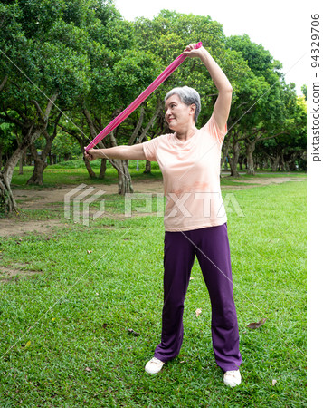 Pleasant entertainment at the airport, where women smile and use the power belt exercise on the grass, as well as enjoy the fresh air of nature in the park. 94329706