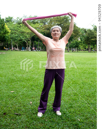 Pleasant entertainment at the airport, where women smile and use the power belt exercise on the grass, as well as enjoy the fresh air of nature in the park. 94329709