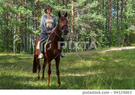 Woman in casual clothes rides a horse in early spring Woman in casual clothes rides a horse in early spring 94329863