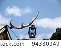 An oil lantern hanging on a deer horn hanger against the blue sky 94330949