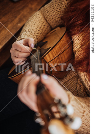 Domra Folk Musical Instrument in womans hand. Female hands with 4 strings Natural Wood Handmade Musical Instrument Domra Close up Domra Folk Musical Instrument in womans hand. Female hands with 4 strings Natural Wood Handmade Musical Instrument Domra Close up 94331198