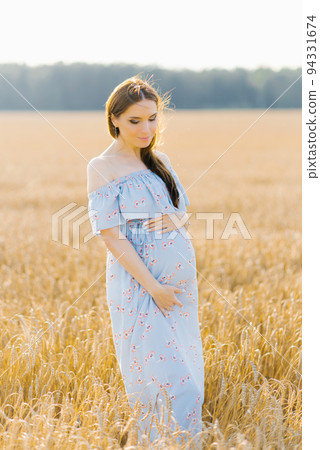 Pregnant brown-haired woman on maternity leave in a high Barley-wheat field 94331674