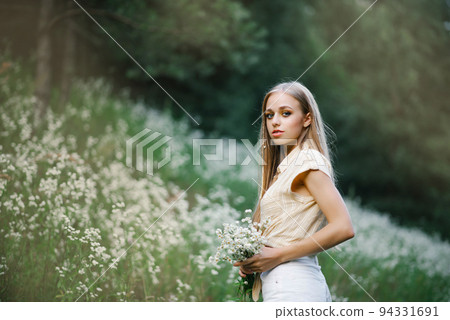 Portrait of a sweet gentle girl in a field of white flowers Portrait of a sweet gentle girl in a field of white flowers 94331691