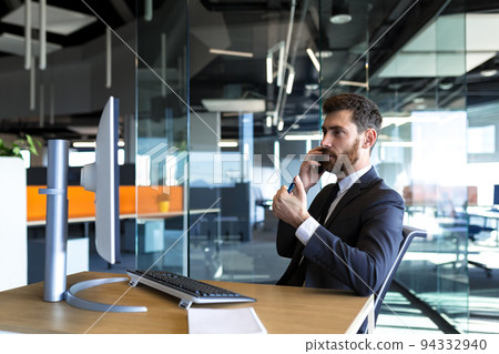 Serious and thoughtful male entrepreneur working in the office at the computer in a business suit 94332940