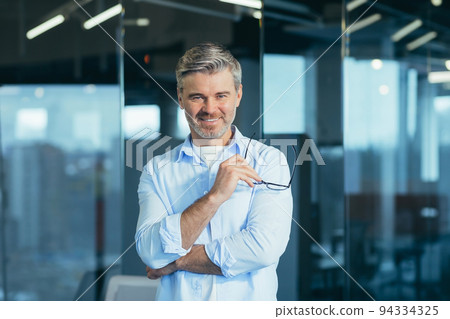Happy bearded businessman entrepreneur startup owner standing in modern office looking at camera, smiling young hipster, creative man posing in workspace, business portrait Happy bearded businessman entrepreneur startup owner standing in modern office looking at camera, smiling young hipster, creative man posing in workspace, business portrait 94334325