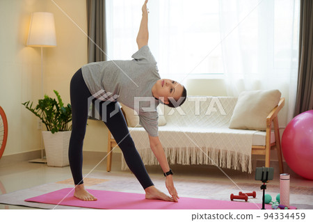 Woman practicing triangle yoga pose when working out at home 94334459