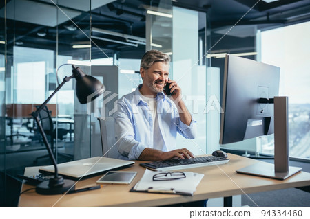 Experienced worker gray-haired businessman works at the computer in a modern office 94334460