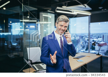 Successful boss working in a modern office, gray-haired businessman talking on the phone Successful boss working in a modern office, gray-haired businessman talking on the phone 94334543