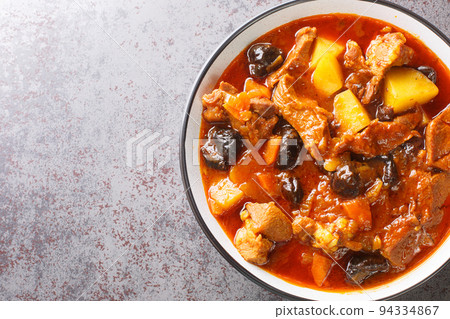 Spicy lamb stew with prunes, tomatoes, potatoes and saffron close-up on a plate on the table. horizontal top view 94334867