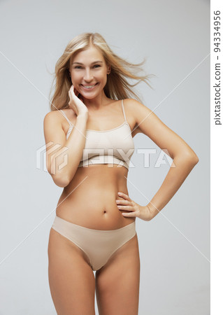Young pretty slim 35 years old woman in cotton inner wear isolated over gray studio background. Wellness, wellbeing, fitness, diet, natural beauty of female body 94334956