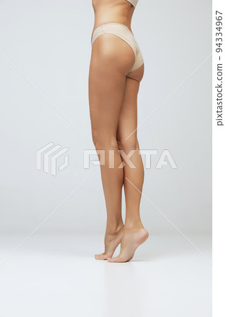Legs and buttocks. Cropped image of female tanned body of young woman in underwear isolated on gray background. Wellness, weight loss, treatment, health care, fitness Legs and buttocks. Cropped image of female tanned body of young woman in underwear isolated on gray background. Wellness, weight loss, treatment, health care, fitness 94334967