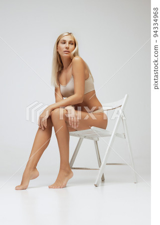 Studio shot of young charming slim girl in grey cotton underwear isolated over gray background. Wellness, fitness, diet, fashion, natural beauty of female body Studio shot of young charming slim girl in grey cotton underwear isolated over gray background. Wellness, fitness, diet, fashion, natural beauty of female body 94334968