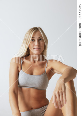 Young pretty slim 35 years old woman in cotton inner wear isolated over gray studio background. Wellness, wellbeing, fitness, diet, natural beauty of female body Young pretty slim 35 years old woman in cotton inner wear isolated over gray studio background. Wellness, wellbeing, fitness, diet, natural beauty of female body 94334969