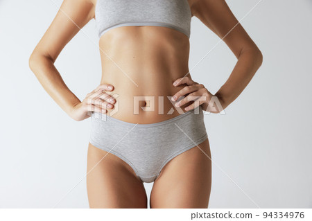 Cropped image of slim female body in cotton underwear isolated over grey studio background. Concept of beauty, body and skin care, fitness, health, spa Cropped image of slim female body in cotton underwear isolated over grey studio background. Concept of beauty, body and skin care, fitness, health, spa 94334976