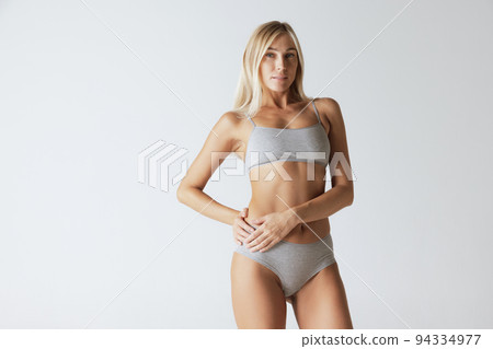 Young pretty slim 35 years old woman in cotton inner wear isolated over gray studio background. Wellness, wellbeing, fitness, diet, natural beauty of female body Young pretty slim 35 years old woman in cotton inner wear isolated over gray studio background. Wellness, wellbeing, fitness, diet, natural beauty of female body 94334977