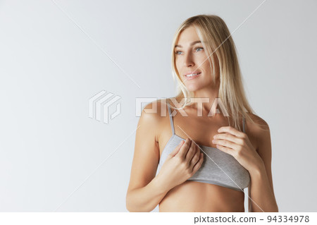 Half-length portrait of charming blonde, young woman with long straight hair smiling and looking away with happy face expression. Beauty, fashion, woman's health Half-length portrait of charming blonde, young woman with long straight hair smiling and looking away with happy face expression. Beauty, fashion, woman's health 94334978