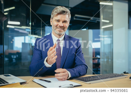 An experienced manager looks at the camera and smiles, a businessman claps his hands on a video call, as a sign of praise and support to interlocutors 94335081