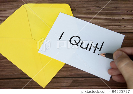 Hand writing I quit text on white notepad with yellow envelope background. Employment concept 94335757